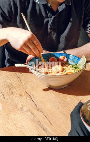 Mann isst Ramen mit Stäbchen. Professionelle Studio-Leuchte Stockfoto