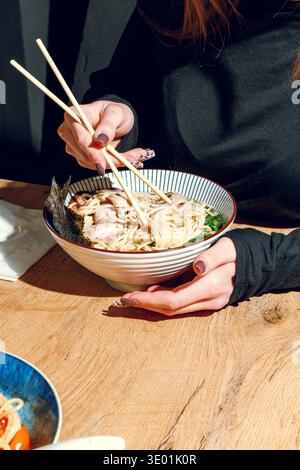 Mann isst Ramen mit Stäbchen. Professionelle Studio-Leuchte Stockfoto