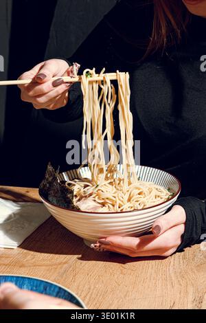 Mann isst Ramen mit Stäbchen. Professionelle Studio-Leuchte Stockfoto