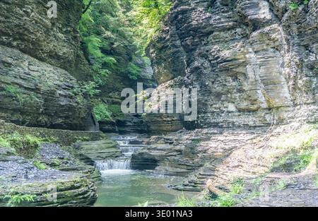 Ein felsiger Canyon mit einem kleinen Bach, der durch ihn fließt. Das Wasser ist klar und die Felsen sind zerklüftet. Die Szene ist friedlich und ruhig Stockfoto