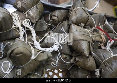 Bananenblätter umhüllte Pakete, bekannt als Khao Tom Mat, ein klebriger Reisknödel, ein beliebter Snack für Street Food in Bangkok, Thailand Stockfoto