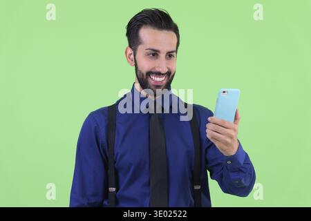 Studio-Aufnahme eines jungen gutaussehenden, bärtigen persischen Geschäftsmannes vor grünem Hintergrund Stockfoto