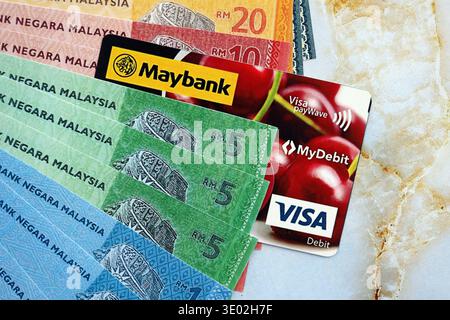 KIEW, UKRAINE - 28. JANUAR 2026 Maybank-Karte und malaysische Ringgit-Geldscheine auf dem Tisch in Nahaufnahme. Maybank ist die beliebteste Bank in Malaysia Stockfoto