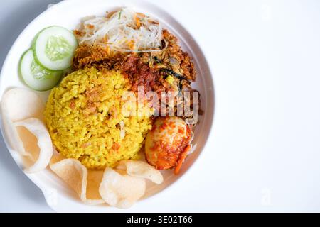 Indonesischer Kurkuma-Reis oder nasi kuning ist aromatischer Reis, der mit Kurkuma und aromatischen Gewürzen zubereitet wird und mit traditionellen Beilagen serviert wird Stockfoto