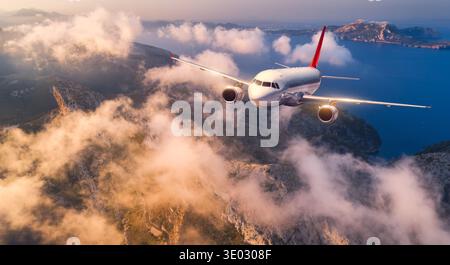 Kommerzielles Flugzeug, das über hohe Berge, Meer und Wolken fliegt Stockfoto