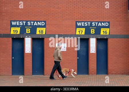 Mann geht mit Hund vorbei an Drehkreuzen im Hampden Park, dem National Stadium, Glasgow, Schottland, Großbritannien Stockfoto