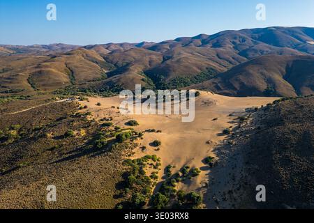 Aus der Vogelperspektive der sanften goldenen Sanddünen von Ammothines auf der Insel Limnos, Griechenland, die die windgekräuselte Wüstenlandschaft und die karge Landschaft zeigt Stockfoto