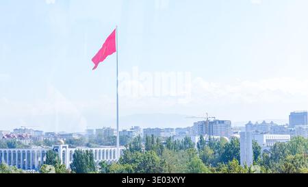 Bischkek, Kirgisistan - 01. Oktober 2024: Kirgisistan-Flagge auf dem Ala-Too-Platz in Bischkek, mit lebendigem Grün und Stadtbild im Stockfoto