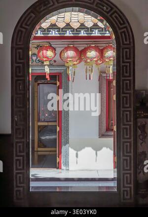 Samut Prakan, Thailand - 11. Januar 2025 - Ein Blick durch das komplizierte bogenförmige Portal von Xian Lo Dai Tien Gong zieht den Blick in einen sonnenverwöhnten Hof Stockfoto
