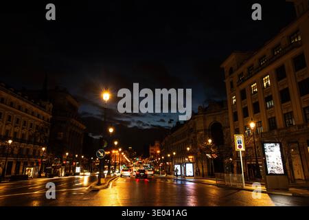 Blick auf die Calle Alcalá im Zentrum von Madrid während der blauen Stunde, mit einem dramatischen Wolkenhimmel über der historischen Architektur Stockfoto