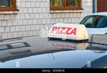 Pizzalieferwagen Dachschild mit rotem PIZZATEXT Nahaufnahme des beleuchteten Take-away-Toppers am Fahrzeug mit Reflektion Lieferservice des lokalen Restaurants f Stockfoto