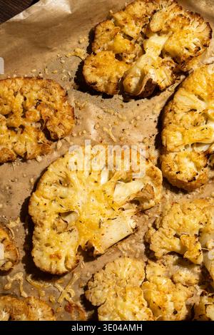 Eine Nahaufnahme von gerösteten Blumenkohlsteaks, gewürzt mit Gewürzen und Kräutern auf einem Backblech. Dieses gesunde Gericht bietet eine aromatische pflanzliche Alternative Stockfoto