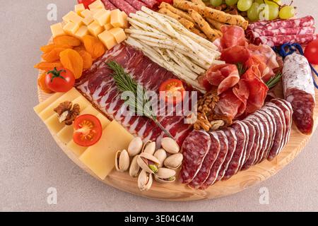 Eine schön gestaltete Wurstplatte mit einer Auswahl an Wurstwaren, Käse, Nüssen, Trauben, Kirschtomaten, und getrocknete Früchte auf einer Holzplatte Stockfoto