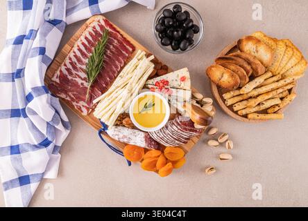 Eine elegante Käse- und Wurstplatte, die wunderschön mit verschiedenen Käsesorten, Wurstwaren, Nüssen und getrockneten Früchten arrangiert ist, begleitet von einer Seite von bre Stockfoto