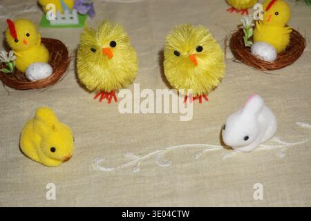 Osterdekoration mit Küken, Hühnern, Kaninchen und bunten Eiern, die um eine Glasvase mit Blumen angeordnet sind, festliche Frühlingsausstellung. Stockfoto