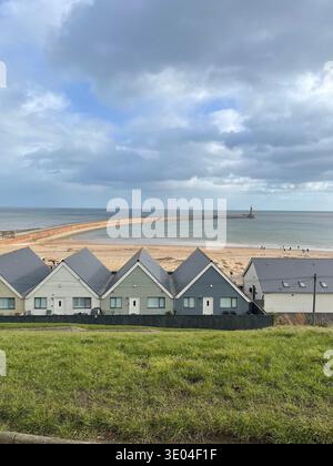 Strandhäuser mit Blick auf Roker Beach und Roker Pier Lighthouse an der Nordseeküste, Sunderland, Tyne and Wear, England, Großbritannien Stockfoto
