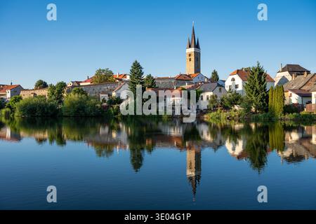 Ein breiter Panoramablick auf die historische Stadt Telč mit ihren bunten Gebäuden und Kirchtürmen, die sich in der ruhigen Oberfläche eines Teichs unter einem klaren Wasser spiegeln Stockfoto