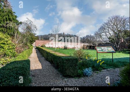 Farbenfrohe Straßenszenen in der mittelalterlichen Stadt Dunster in den Priory Gardens der St. George's Church mit Blick auf den Conygar Tower aus dem 17. Jahrhundert Stockfoto