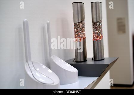 Nahaufnahme moderner Badezimmeraccessoires in einem Regal in einem Ausstellungsraum. Im Vordergrund zwei elegante weiße Toilettenbürstenhalter mit... Stockfoto