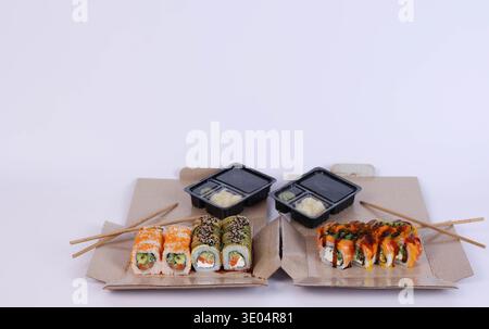 Sushi liegt in Schachteln auf weißem Hintergrund. Lieferung Stockfoto