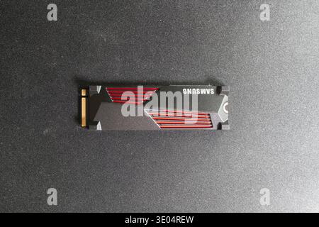 Hochwinkelaufnahme einer schwarz-roten Samsung NVMe SSD mit sichtbarem PCIe-Anschluss auf dunkler strukturierter Oberfläche. Stockfoto