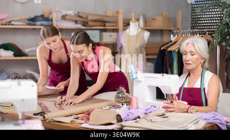 Ältere Schneiderin arbeitet mit Modedesignern in einem Atelier Stockfoto