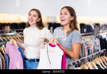 Einkaufsraum des Bekleidungsgeschäfts mit jungen Frauen, die Jacken und Pullover aussuchen Stockfoto