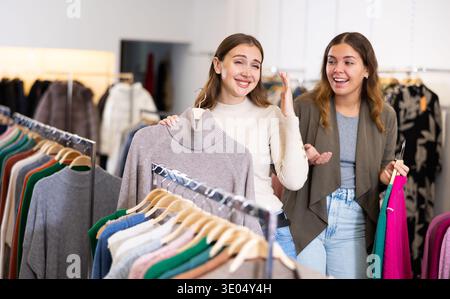Porträt zweier positiver Frauen, die Cardigan im Bekleidungsgeschäft wählen Stockfoto