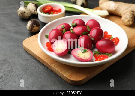 Eingelegte Wachteleier und Zutaten auf schwarzem Tisch, Nahaufnahme Stockfoto