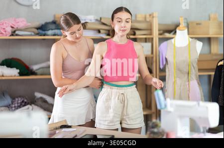 Junge Schneiderin nimmt Körpermaße von erwachsenen Frauen Stockfoto