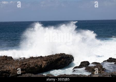 Die starken Wellen krachen gegen die zerklüftete Küste. Der Horizont bleibt in der Entfernung unverändert. Stockfoto