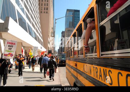 Kinder in einem Schulbus, rechts, sehen pro-Tibet Demonstranten, links, marschieren während des 67. Tibetischen Aufstands. Demonstranten trafen sich in Manhattan, New York City, um Tibets Unabhängigkeit von China zu fordern. Der Tag des Tibetischen Aufstands ist der Tag im Jahr 1959, an dem Tausende Tibeter in Tibet den Palast des heutigen und 14. Dalai Lama umgaben. Der Dalai Lama ist der spirituelle buddhistische Führer der Tibeter weltweit. Die Tibeter umzingelten den Palast 1959, um den Dalai Lama zu schützen, weil sie befürchten, dass die chinesische Regierung ihn entführen würde. Am 17. März 1959 wurde der Dalai Lama zur Flucht gezwungen Stockfoto