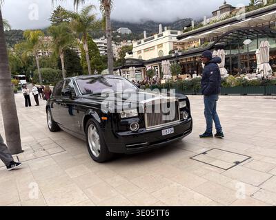 Ein Luxusauto parkt in der Nähe des Cafe de Paris Monte-Carlo in Monaco. Der Mann steht neben dem schwarzen Rolls-Royce Phantom. Stockfoto
