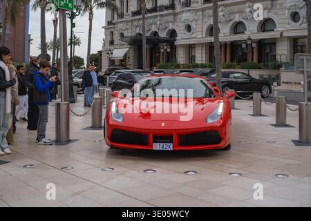 Roter Ferrari 488 vor dem Restaurant Le Louis XV. Touristen, die vor dem opulenten Hoteleingang von Monte Carlo Fotos machen. Stockfoto