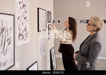 Junge kaukasische Frau und kaukasische Frau mittleren Alters, die Kunstwerke betrachten Stockfoto