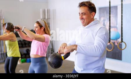 Gruppe von Menschen, die im Fitnessstudio mit Kettlebells trainieren Stockfoto