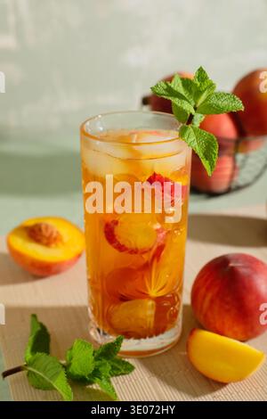 Glas leckerer Pfirsicheistee auf grünem Grunge-Hintergrund, Nahaufnahme Stockfoto