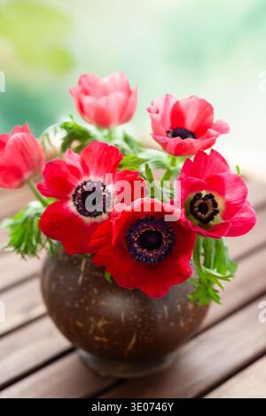 Elegantes Strauß aus roten Anemonenblüten in einer rustikalen Vase, die ein natürliches und romantisches Stillleben schaffen, ideal für Blumen, Wohnkultur und Botanik Stockfoto