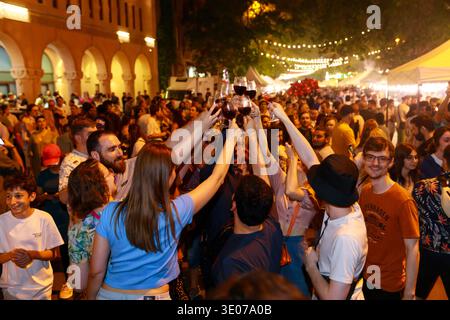 Bei den Weintagen in Jerewan versammeln sich Besucher unter Abendlichtern, während Freunde im Herzen der Feier mit Rotwein anstoßen. Stockfoto