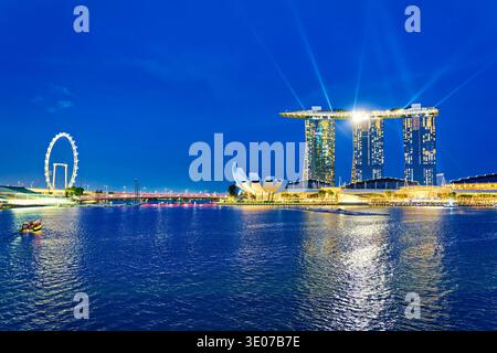 Am Abend versammeln sich die Leute in der Marina Bay, um den Blick auf die Skyline der Stadt und die Reflexionen des Sonnenuntergangs auf dem Wasser zu genießen. Stockfoto