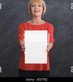 Glückliche Frau mittleren Alters mit weißem Papier Stockfoto