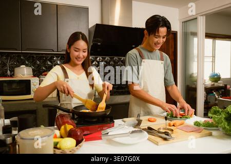 Asiatisches junges Paar, das in der Küche zu Hause kocht Stockfoto