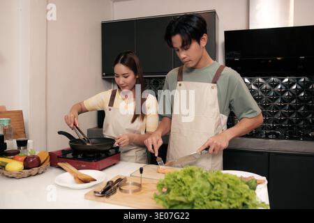 Asiatisches junges Paar, das in der Küche zu Hause kocht Stockfoto
