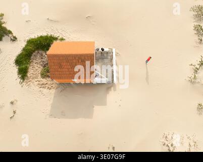 Costa da Caparica, Portugal - 19. Dezember 2024: Aus der Vogelperspektive auf ein einsames Strandhaus mit einem leuchtenden orangefarbenen Dach inmitten der Weite des goldenen san Stockfoto
