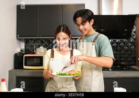 Asiatisches junges Paar, das in der Küche zu Hause kocht Stockfoto