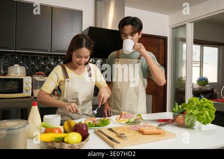 Asiatisches junges Paar, das in der Küche zu Hause kocht Stockfoto