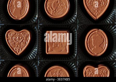 Offene Schachtel mit verschiedenen Pralinen mit kunstvollen dekorativen Stücken, die ordentlich im Inneren angeordnet sind. Stockfoto