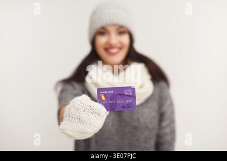 Glückliche Frau in Winterkleidung mit Kreditkarte Stockfoto