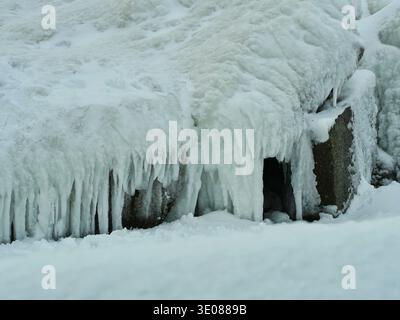 Schneebedeckter Granitbruch vor der gefrorenen Ostsee. Stockfoto