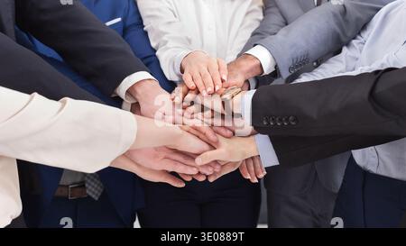 Geschäftsleute, die im Büro Hände zusammenlegen Stockfoto